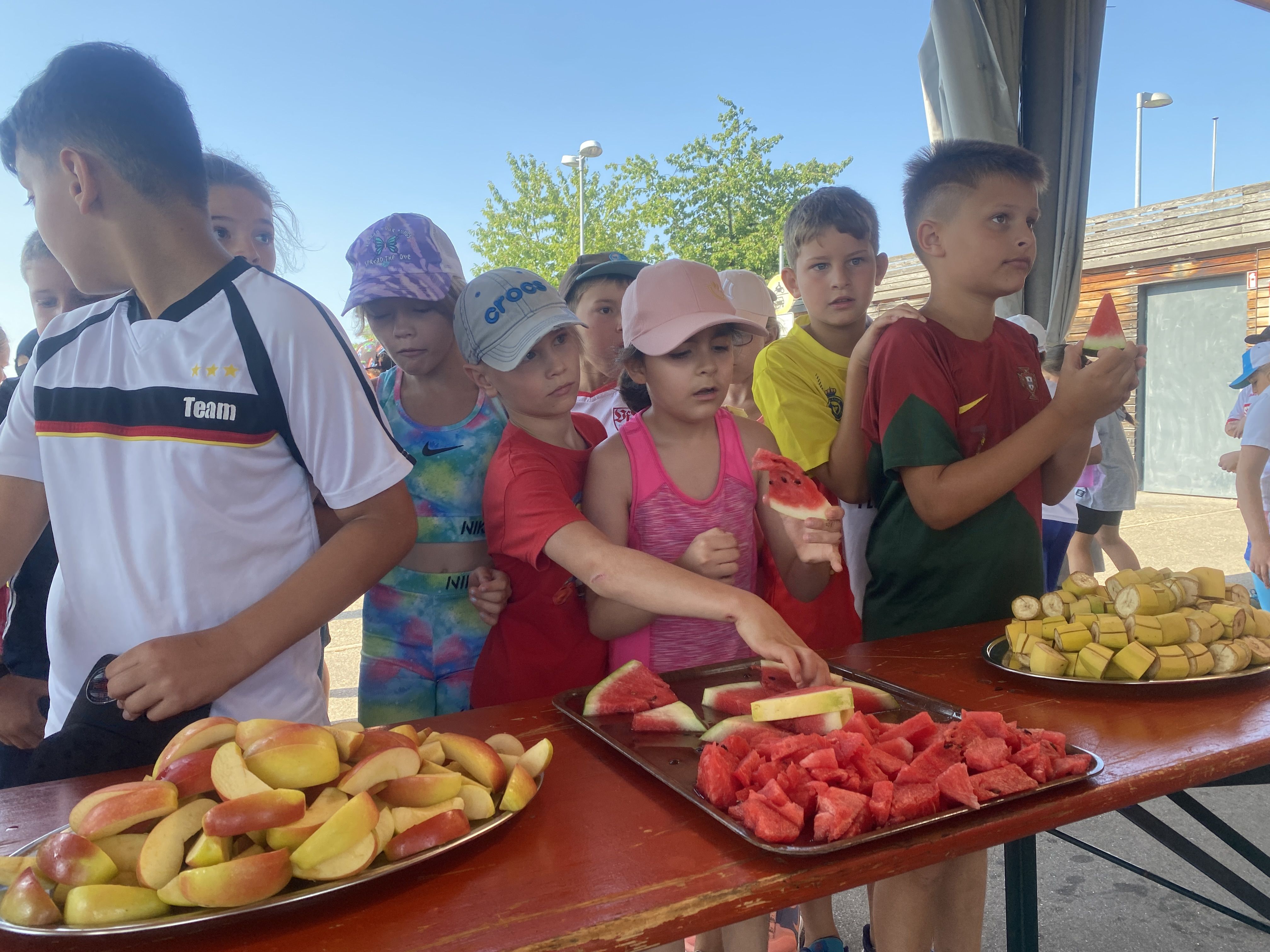 Mehrere Kinder bedienen sich an einem Obstbüfett.