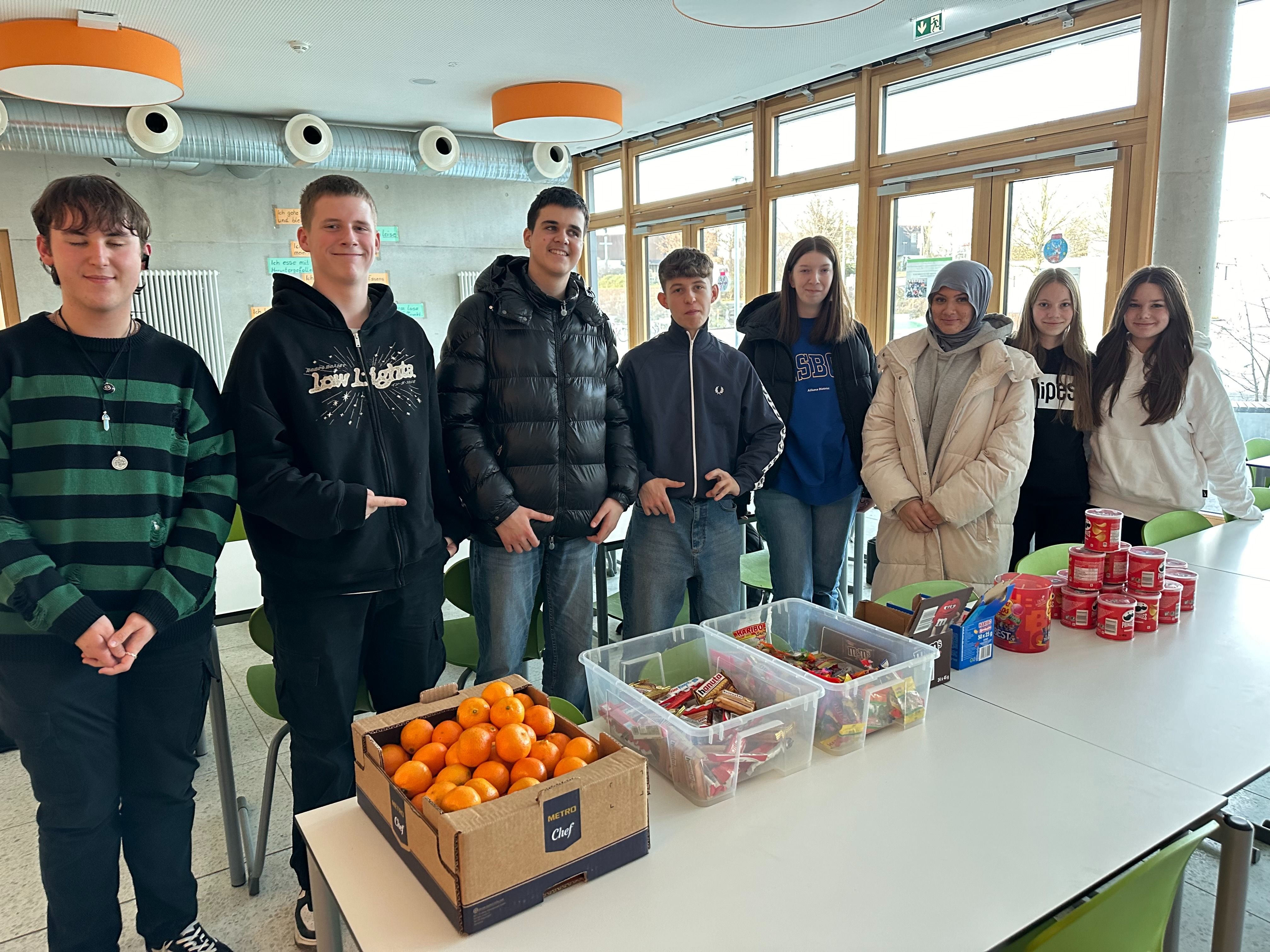 Eine Gruppe Schülerinnen und Schüler steht vor den Geschenken des Fördervereins