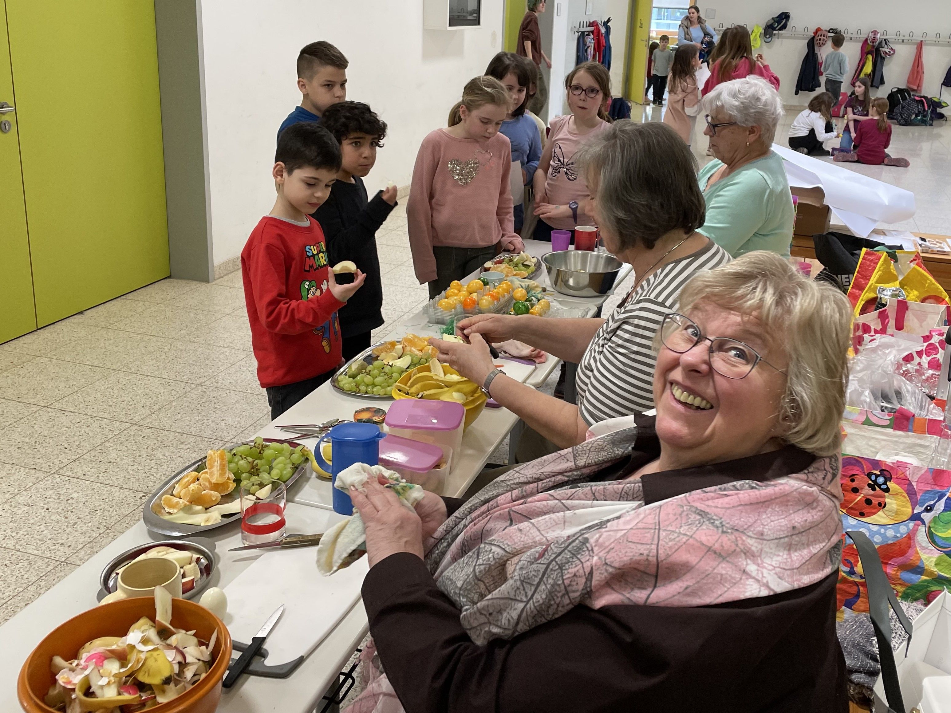 Drei Frauen vom Förderverein schneiden Obst für Kinder.