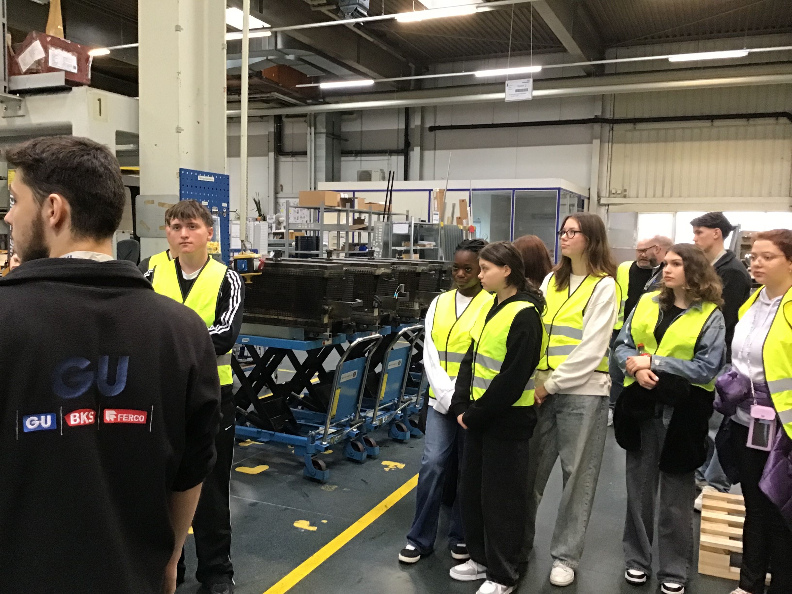 eine Gruppe Schüler bekommt in der Produktionshalle von GU etwas erklärt.
